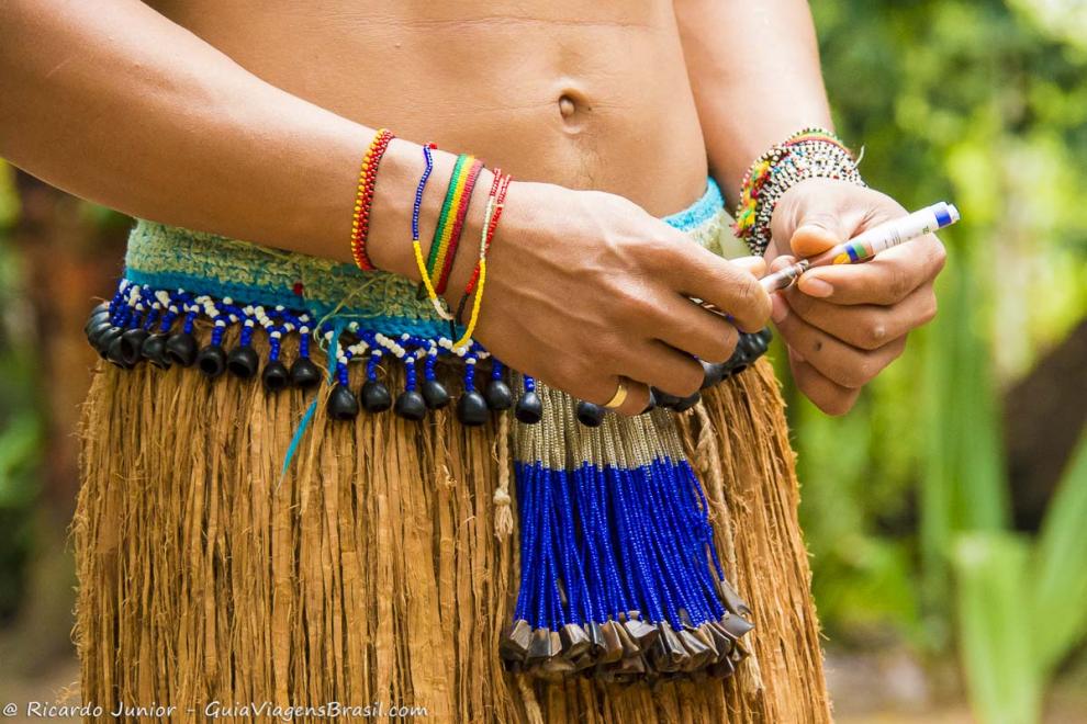 Imagem de um índio com saia de sapê e pulseiras coloridas.